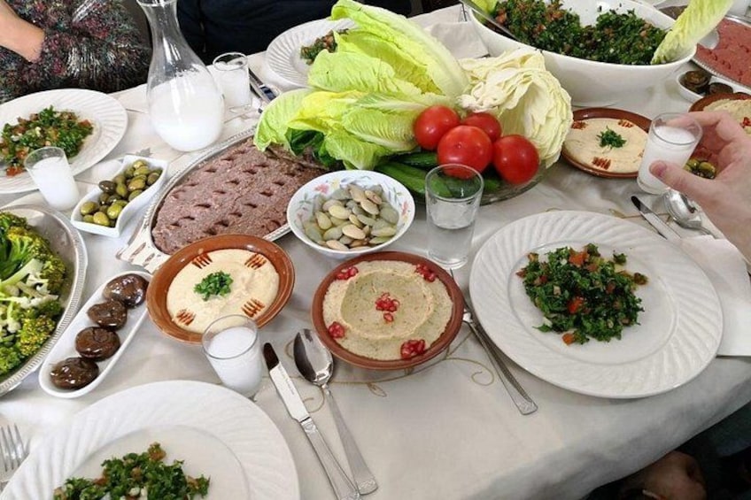 A table with various dishes, including salads, meats, and dips, suggesting a communal meal setting. 5