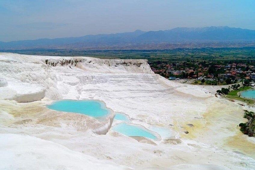 Terraced mineral pools, a distant town, and mountains. 1