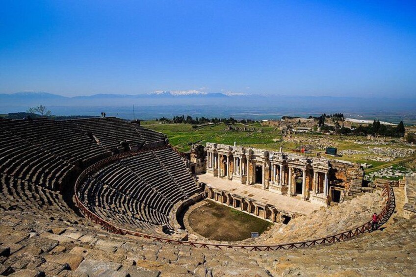 An ancient amphitheater with a partially intact stage and audience seating. 5