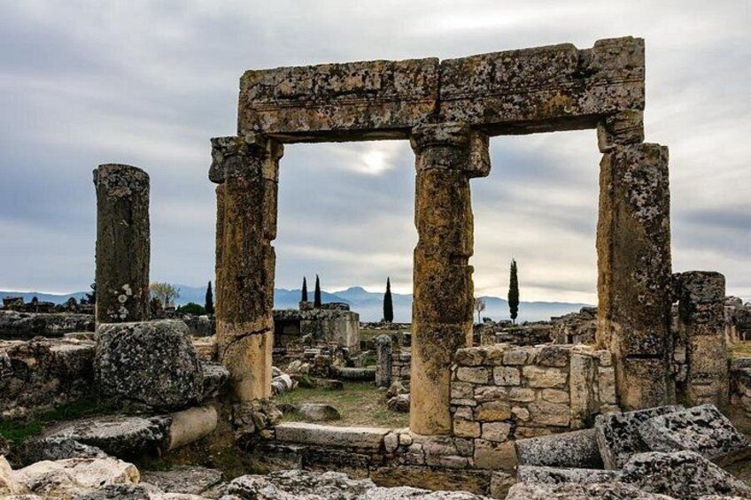 Ancient stone ruins with columns and arches, set against a cloudy sky. 2