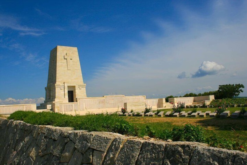 A memorial with a tall monument and a cross, surrounded by a cemetery with headstones. 1