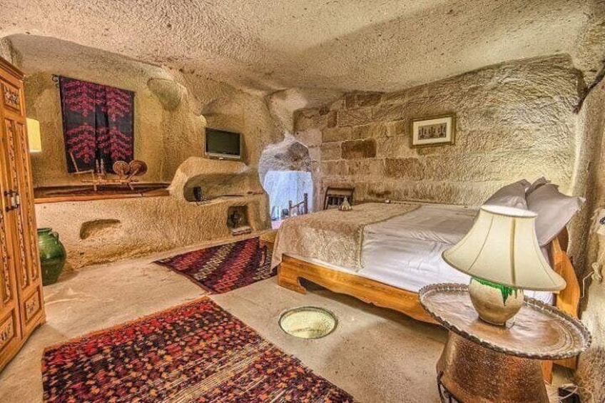 A rustic bedroom with a stone wall, a bed, a wooden cabinet, and a television. 5