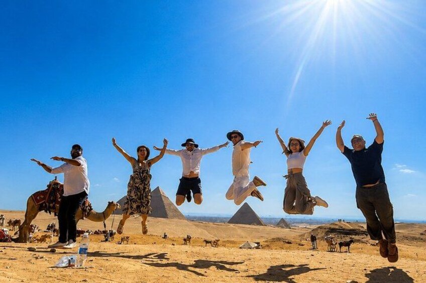 People jumping in a desert with pyramids in the background. 4