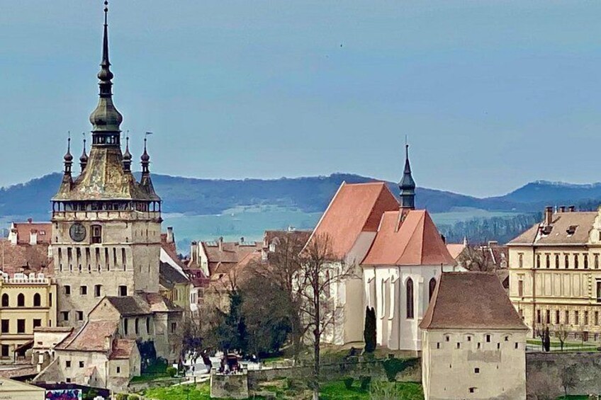 Eine historische Stadt mit einem markanten Kirchengebäude, einem Glockenturm und einem Fluss im Hintergrund. 5