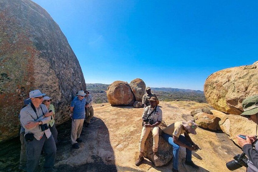 A group of people standing around large boulders in a rocky landscape. 3