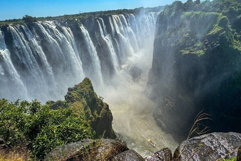 Een grote waterval die over een klif stort, omringd door groen. 1