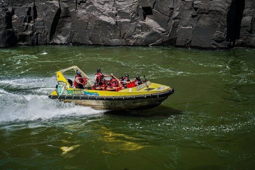 Una lancha inflable amarilla con gente usando chalecos salvavidas rojos en un río. 2