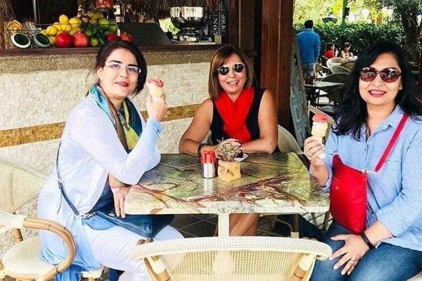 Three people sitting at an outdoor table with drinks and a fruit bowl. 2