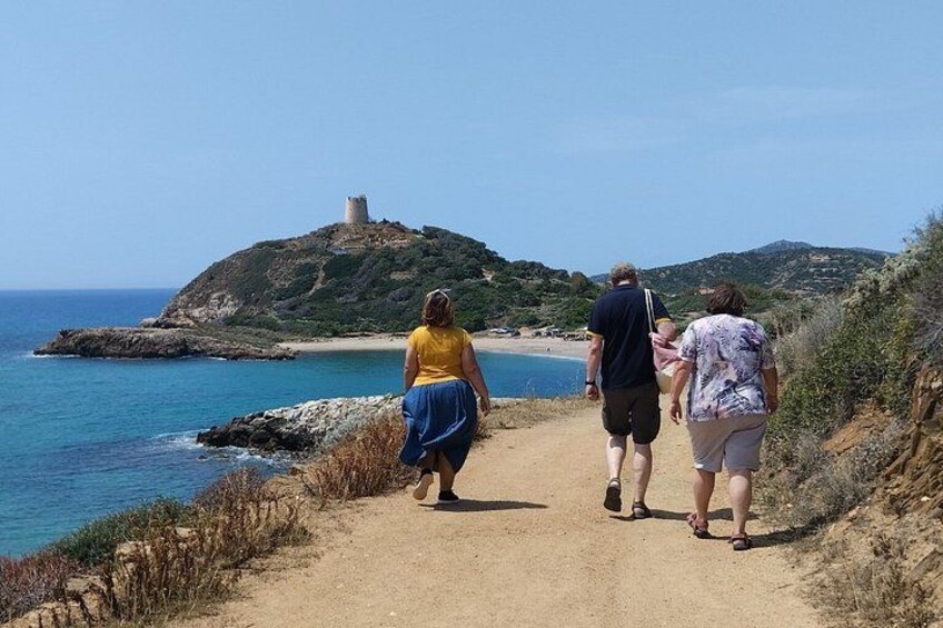 A dirt path along a coastal area with a castle on a hill, the sea, and a clear sky. 2