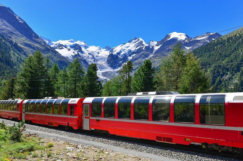 A red train on tracks with snow-capped mountains in the background. 3