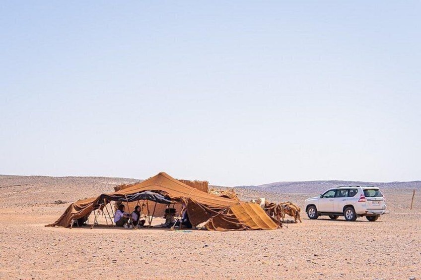 A desert with a tent and a vehicle. 1
