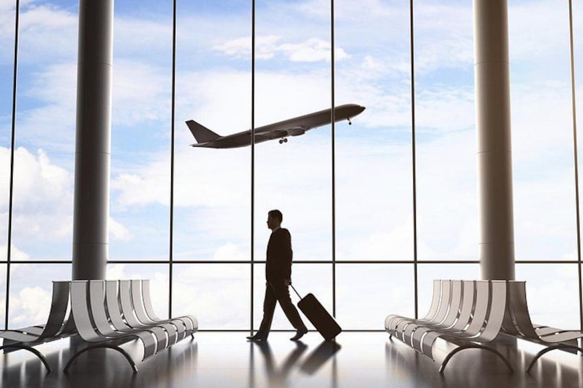 A person walking towards an airplane in an airport terminal with large windows and seating areas. 2