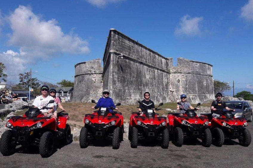 Een groep mensen op rode quad bikes voor een groot, oud stenen gebouw. 1