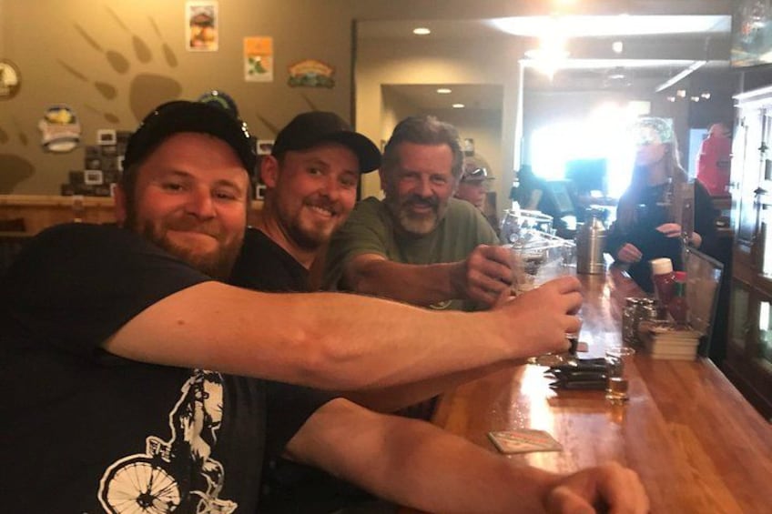 Three people sitting at a bar with drinks. 3