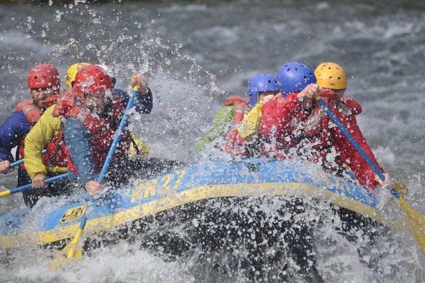 A group of people in a raft navigating through rough waters. 2