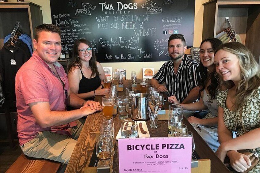 Un grupo de personas sentadas en una mesa en un restaurante, con un letrero que dice 'Bicycle Pizza'. 2