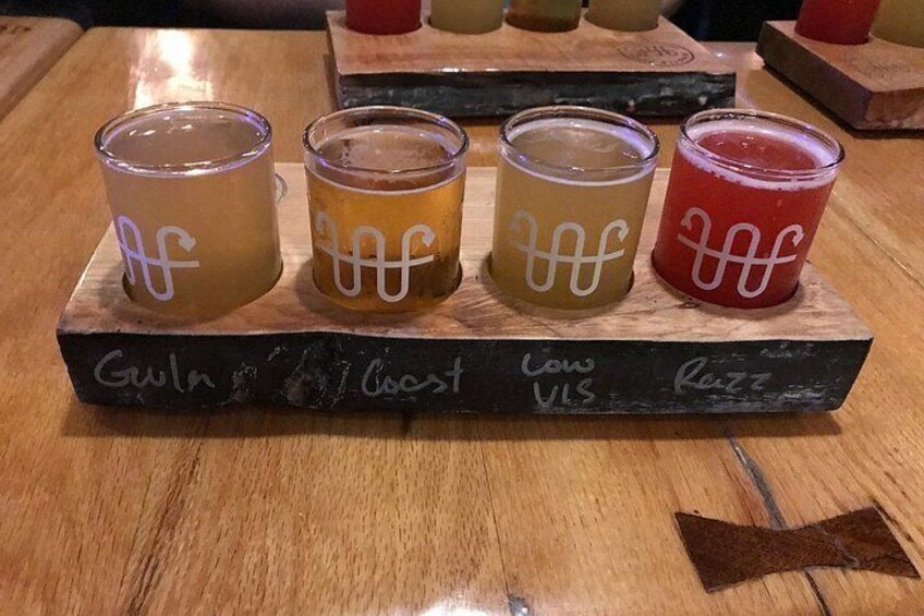 Cuatro vasos de vidrio con líquidos de distintos colores sobre una tabla de madera con etiquetas de texto. 3
