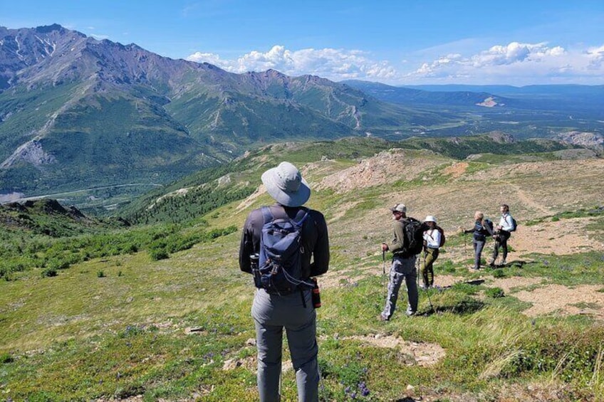 A group of hikers on a mountain trail with a view of distant mountains and a valley. 4