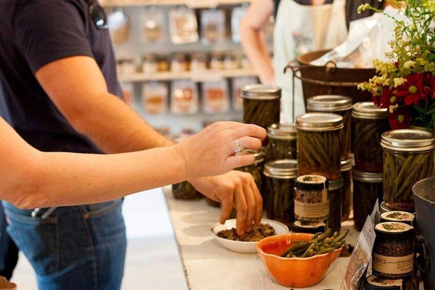 A person selecting preserved vegetables from jars. 5