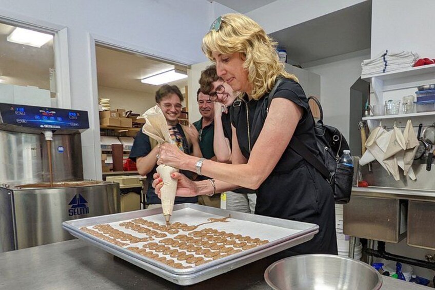 A person decorating cookies with icing on a tray. 3