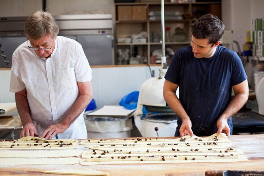 Two individuals working with wooden planks and small objects on a table in a workshop. 3