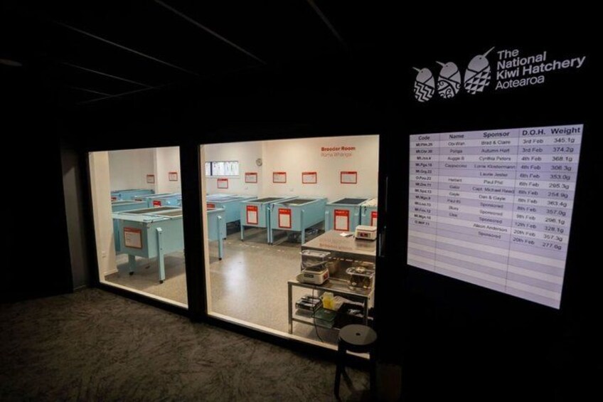 A room with tables and chairs, a display board with text, and a logo on the wall. 3