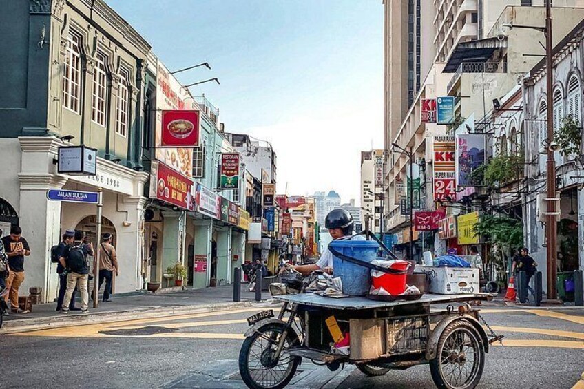 Une scène de rue avec un chariot transportant des marchandises, des bâtiments avec des enseignes et des piétons. 4