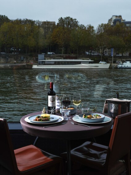 Une table dressée avec des assiettes remplies de nourriture et des verres à vin, placée au bord d’un plan d’eau. 5