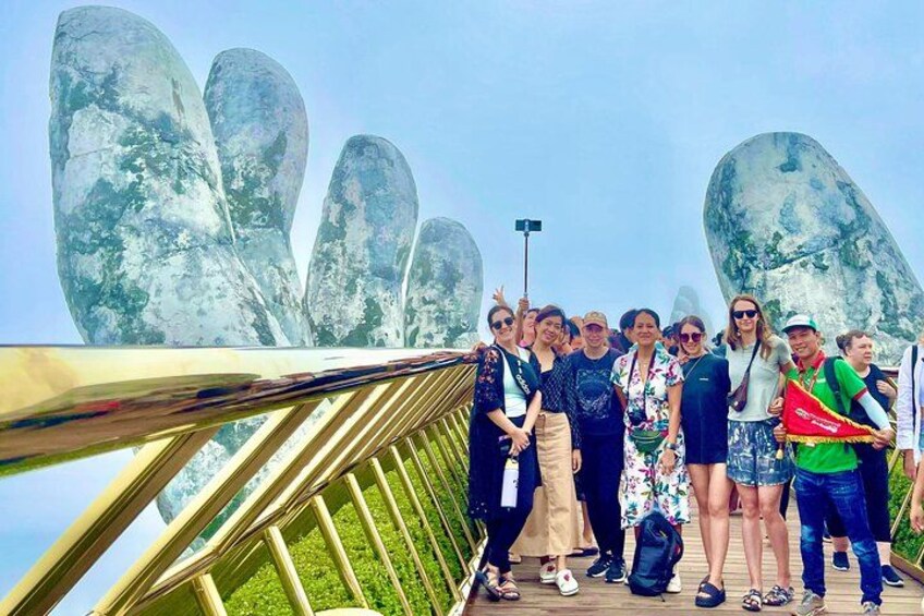 A group of people on a bridge with large rock formations in the background. 1