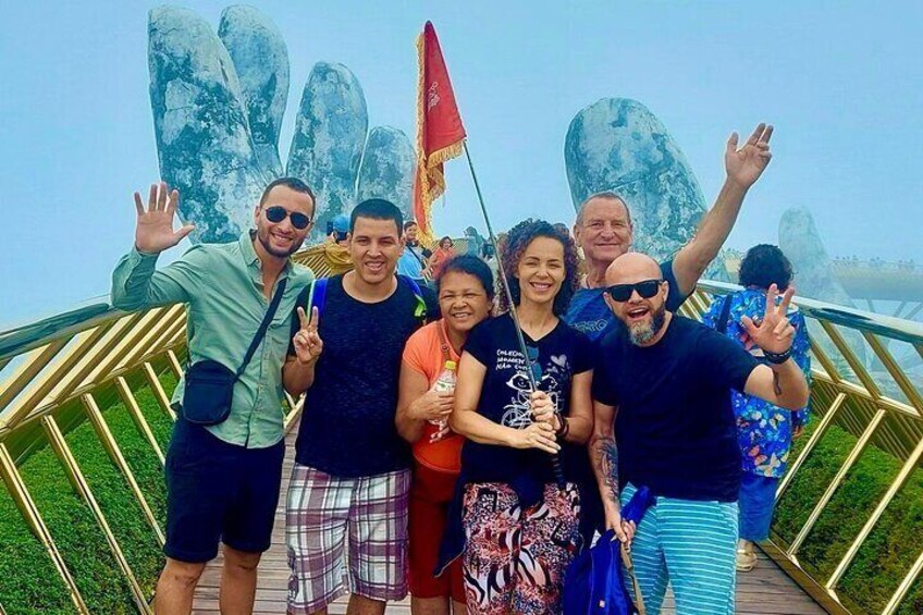 A group of people posing in front of large rock formations with a flag. 4