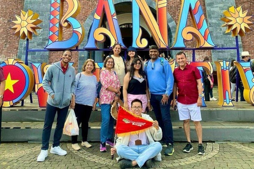 Un grupo de personas de pie frente a un letrero colorido con las letras 'BAN' y una estrella. 2