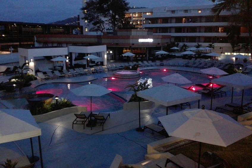 A resort pool area with lounge chairs and umbrellas. 1