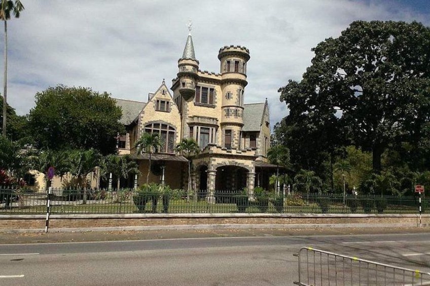 A large, ornate building with a tower and turret, surrounded by a fence and trees. 3