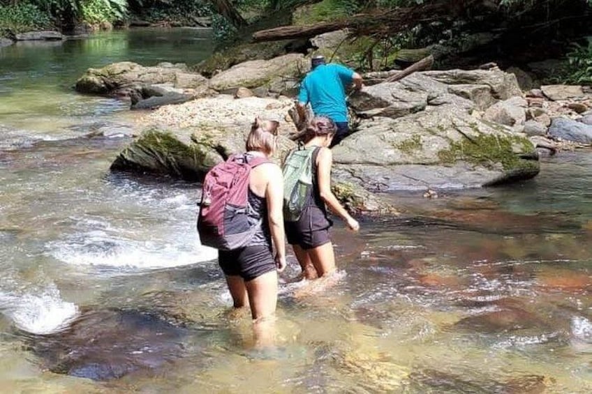 People wading in a river surrounded by rocks and trees. 1