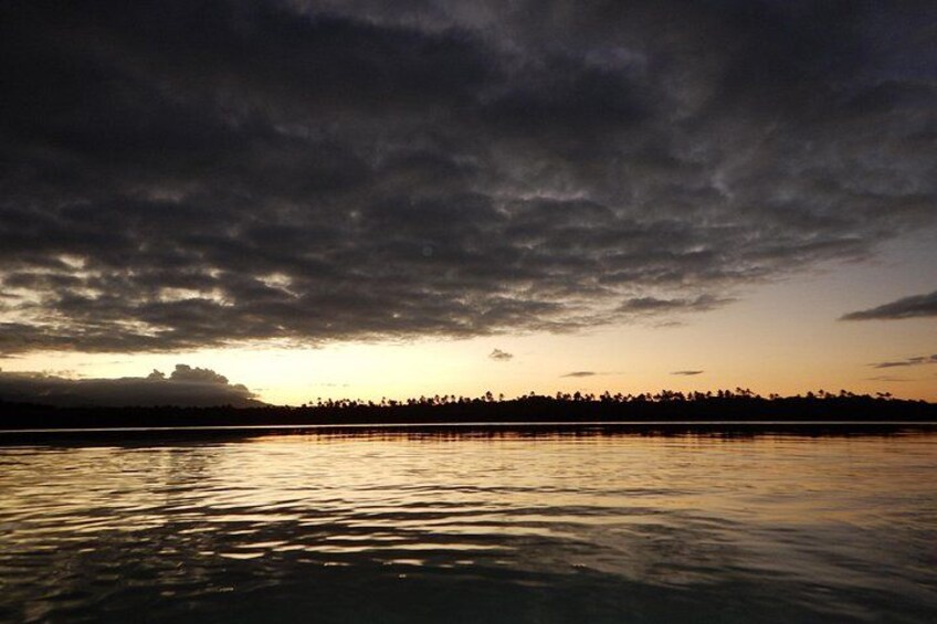 A sunset over a calm body of water with a silhouette of a distant shoreline. 3