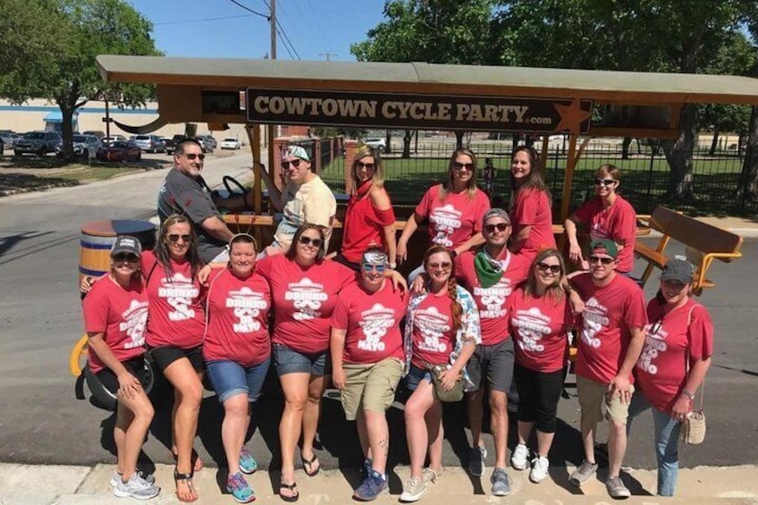 Un grupo de personas posando frente a un letrero que dice 'COWTOWN CYCLE PARTY'. 2
