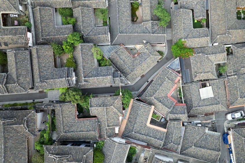An aerial view of a densely packed residential area with closely aligned buildings, narrow streets, and small green spaces. 3