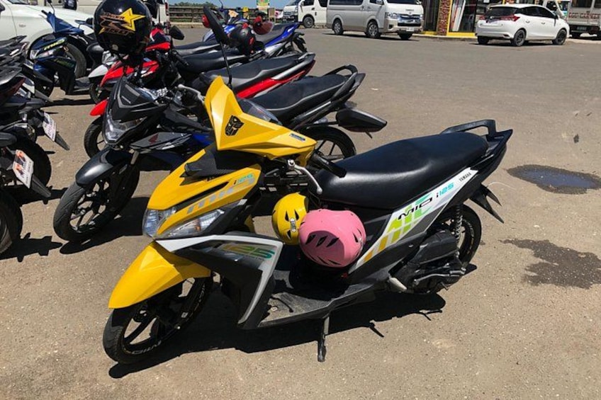A row of parked motorcycles with helmets on them. 5