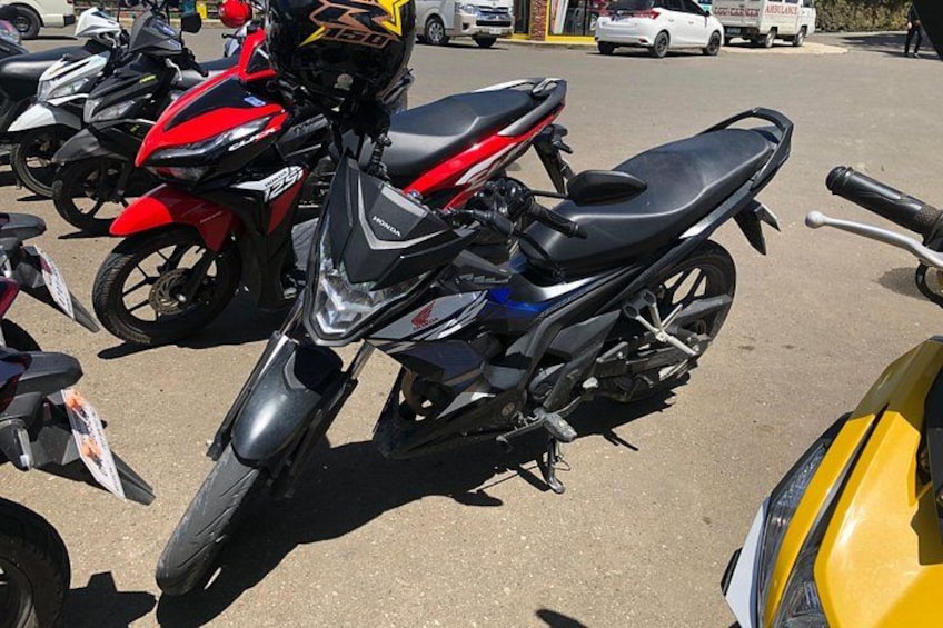 A red and black motorcycle parked in a lot with other motorcycles. 4