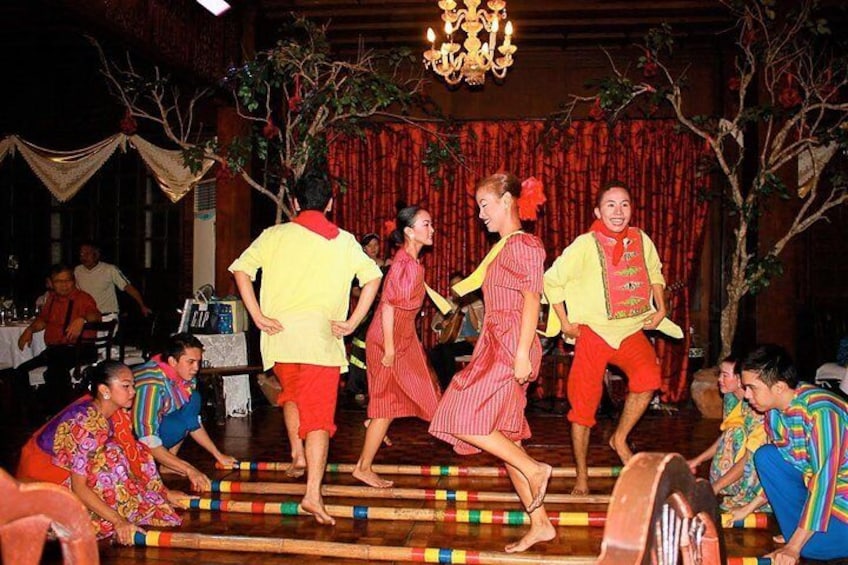 A group performing a traditional dance on a wooden floor with colorful decorations. 1