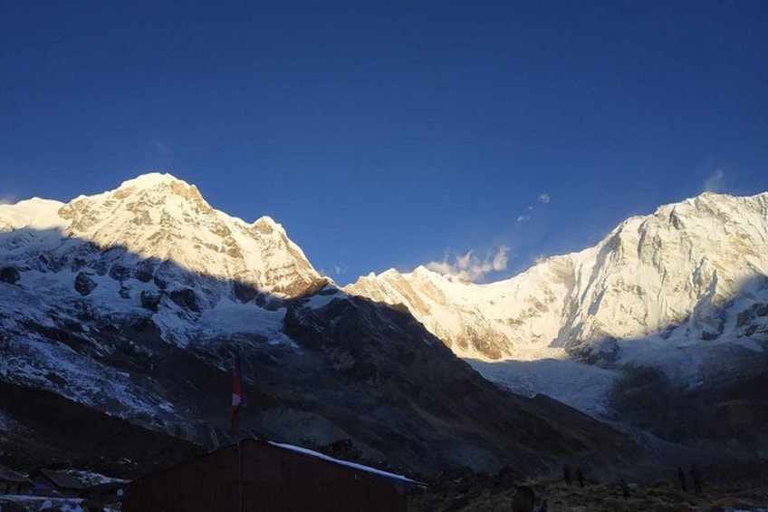 Snow-covered mountains, a clear sky, and a small building. 1