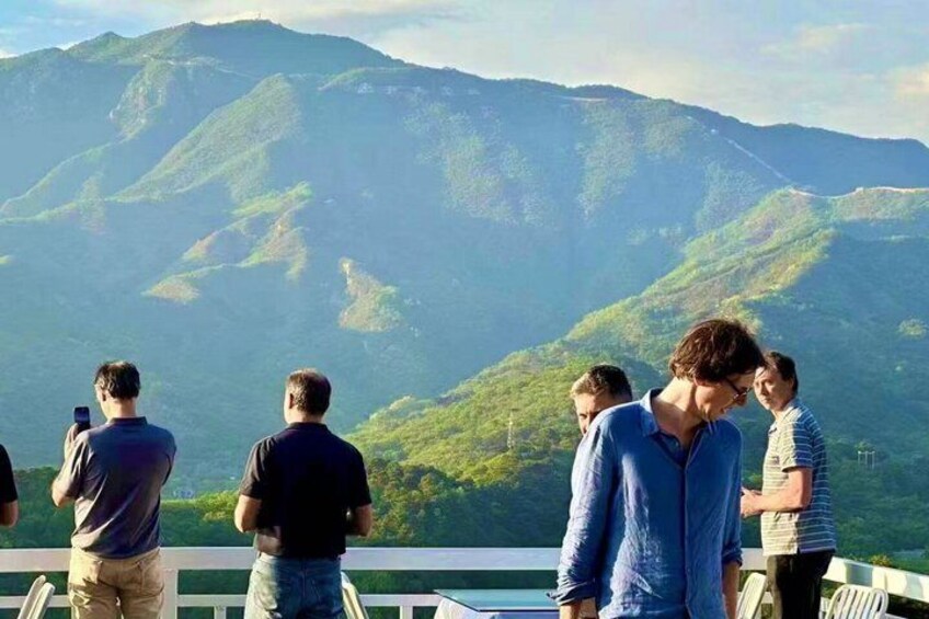 A group of people standing on a balcony overlooking a mountainous landscape. 2