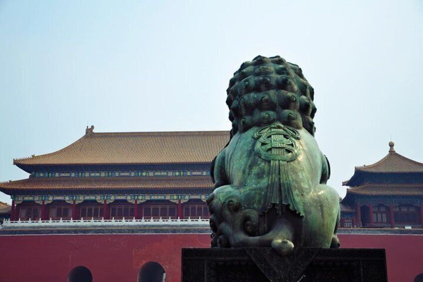 A bronze lion statue in front of a traditional Chinese building with a tiled roof. 1