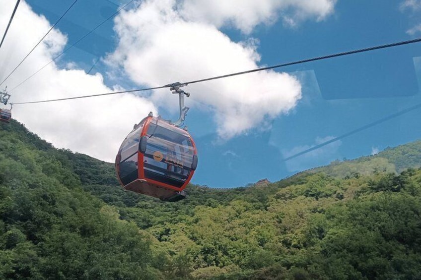 A cable car suspended over a forested mountain. 3
