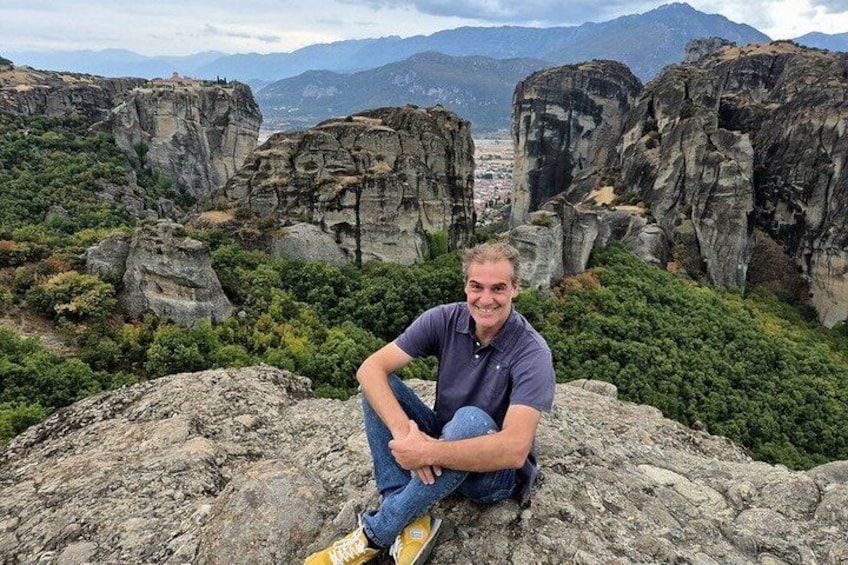 A person sitting on a rock with a mountainous landscape in the background. 2