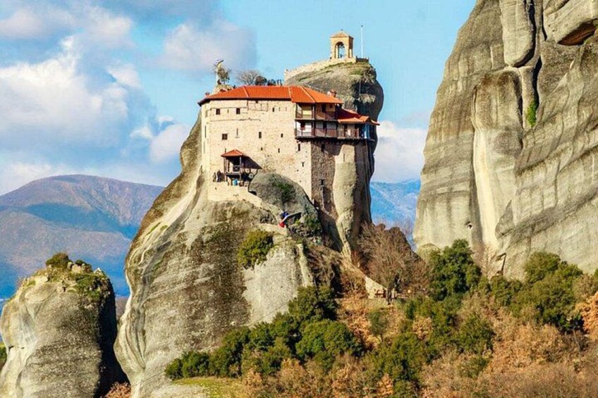 Un monastère perché sur une formation rocheuse, avec un bâtiment au toit rouge et un clocher. 4