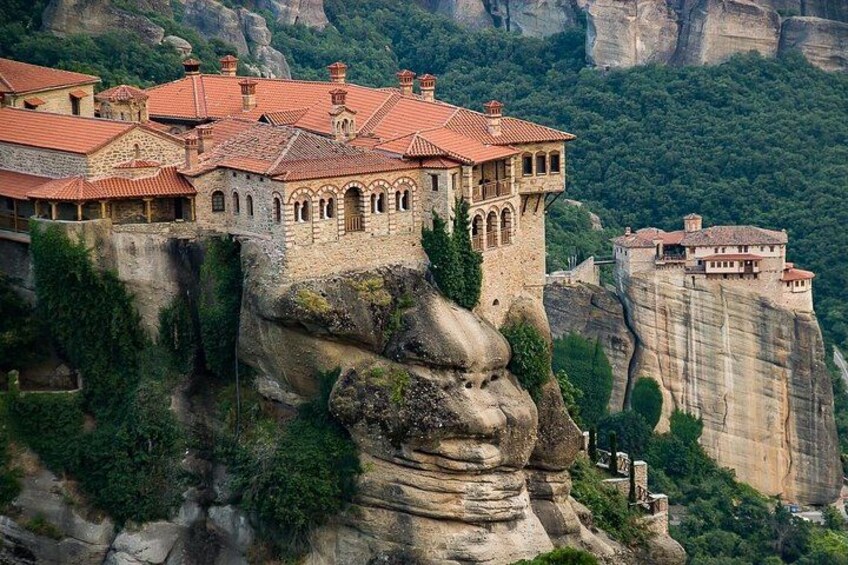 Un monastère perché au sommet d’une falaise, avec des toits recouverts de tuiles rouges et des murs en pierre. 5
