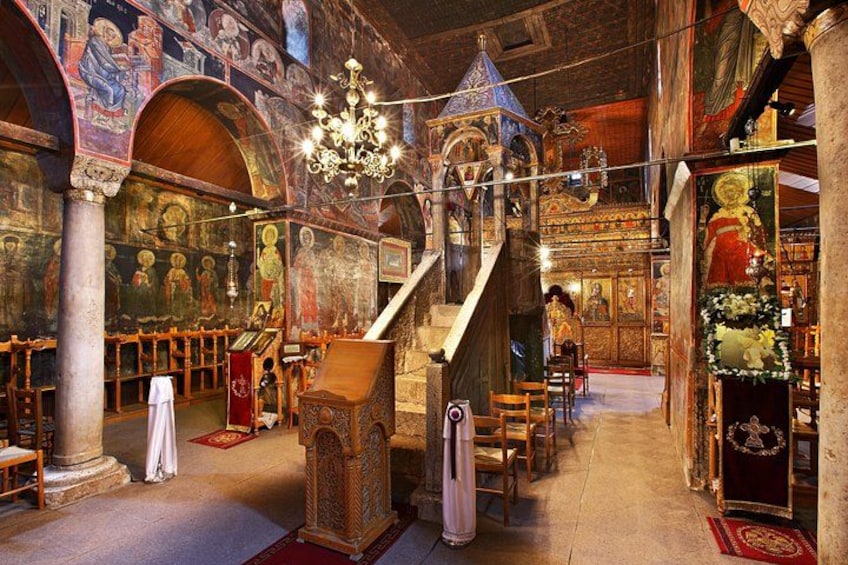 An ornate church interior with a wooden altar, a staircase, and religious iconography. 3