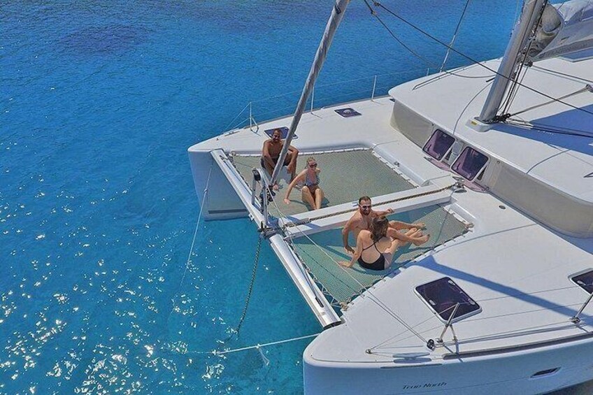 Un velero con gente en la cubierta, agua azul cristalina y cielo despejado. 2