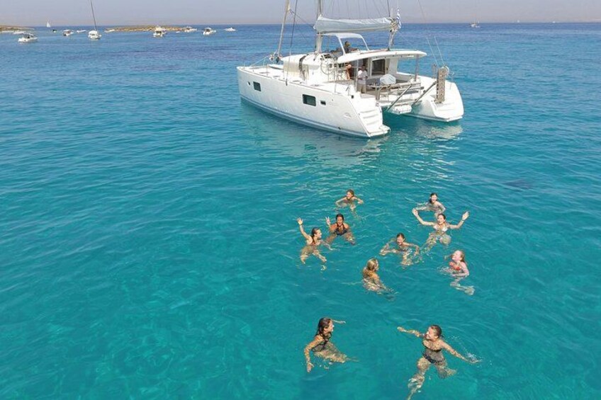 A group of people swimming in turquoise water near a white yacht. 3
